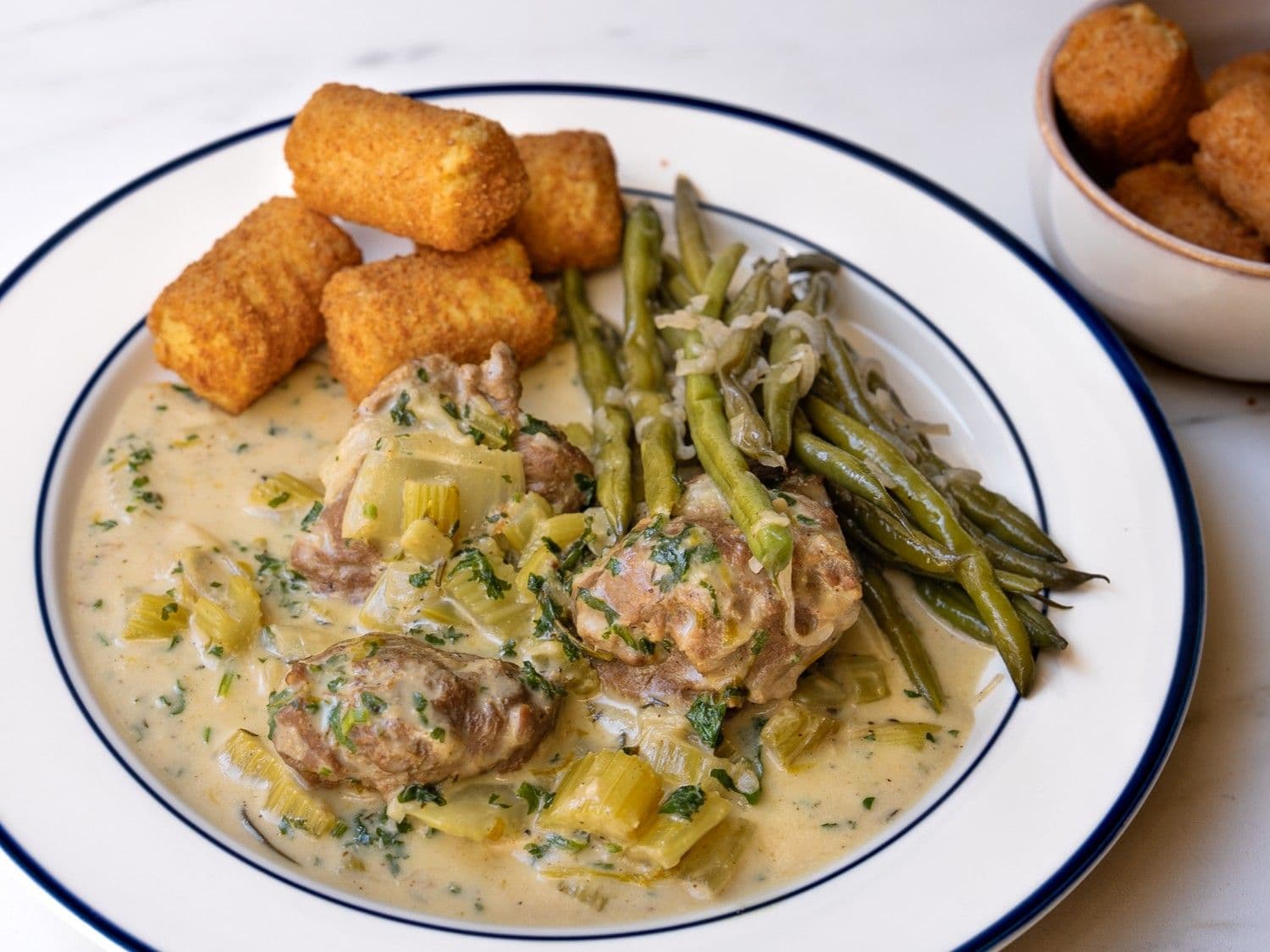 Varkenswangen in seldersaus met boontjes en kroketten