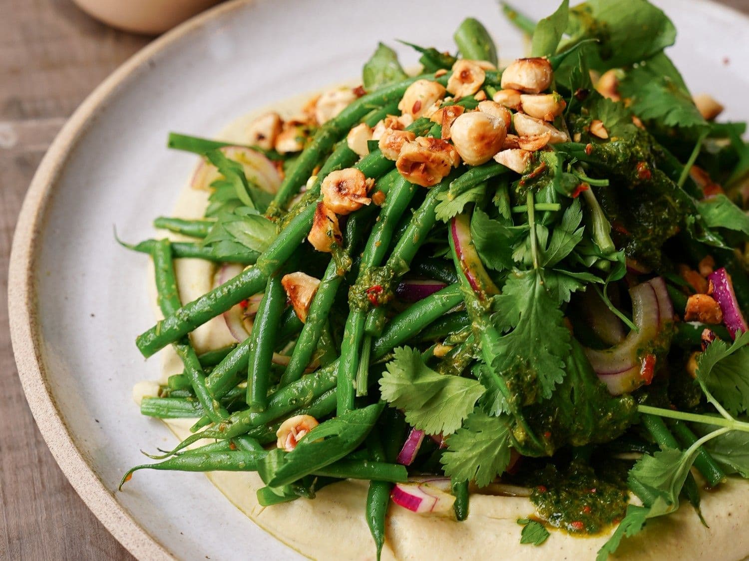 Hummus van witte bonen, salade met groene boontjes, hazelnoten en chermoula