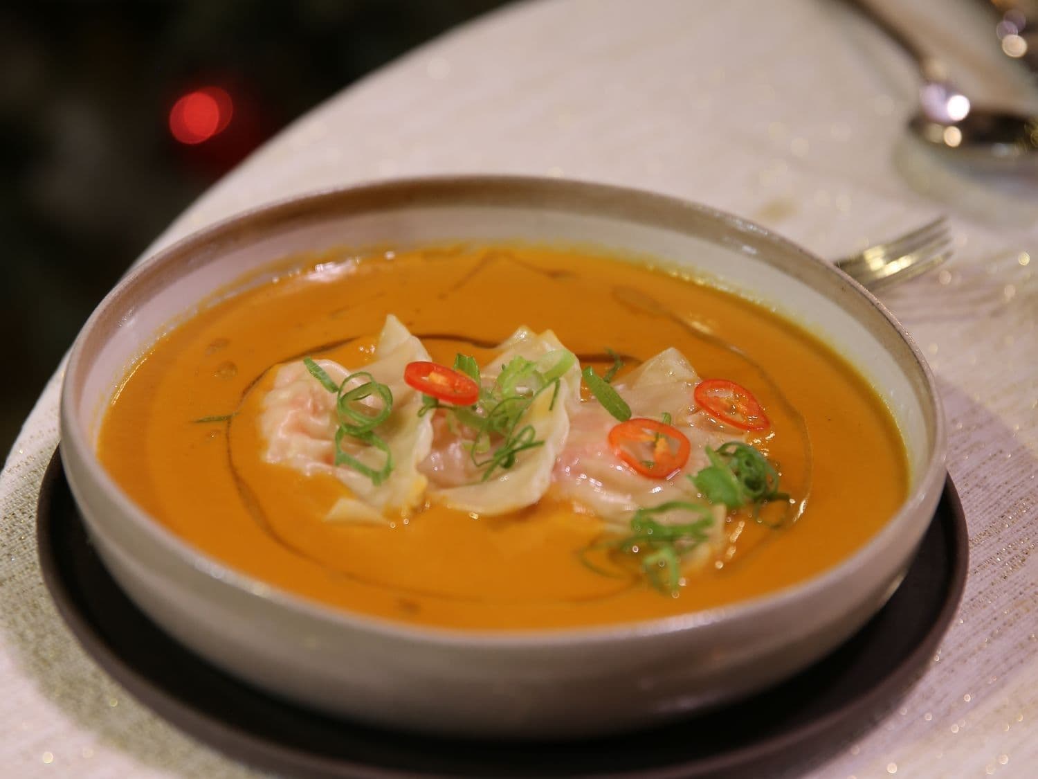 Romige soep van zoete aardappel, dumplings van scampi en limoenbladolie