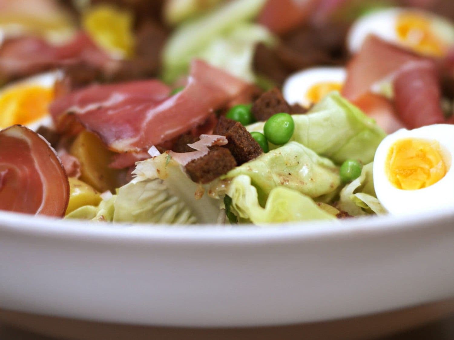 Salade met erwten, rauwe ham en croutons