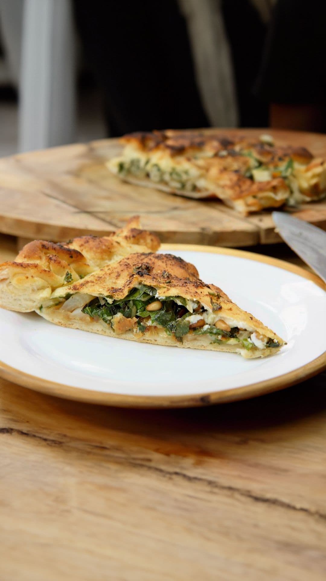 Pizza met gebakken ui, warmoes, feta en pijnboompitten