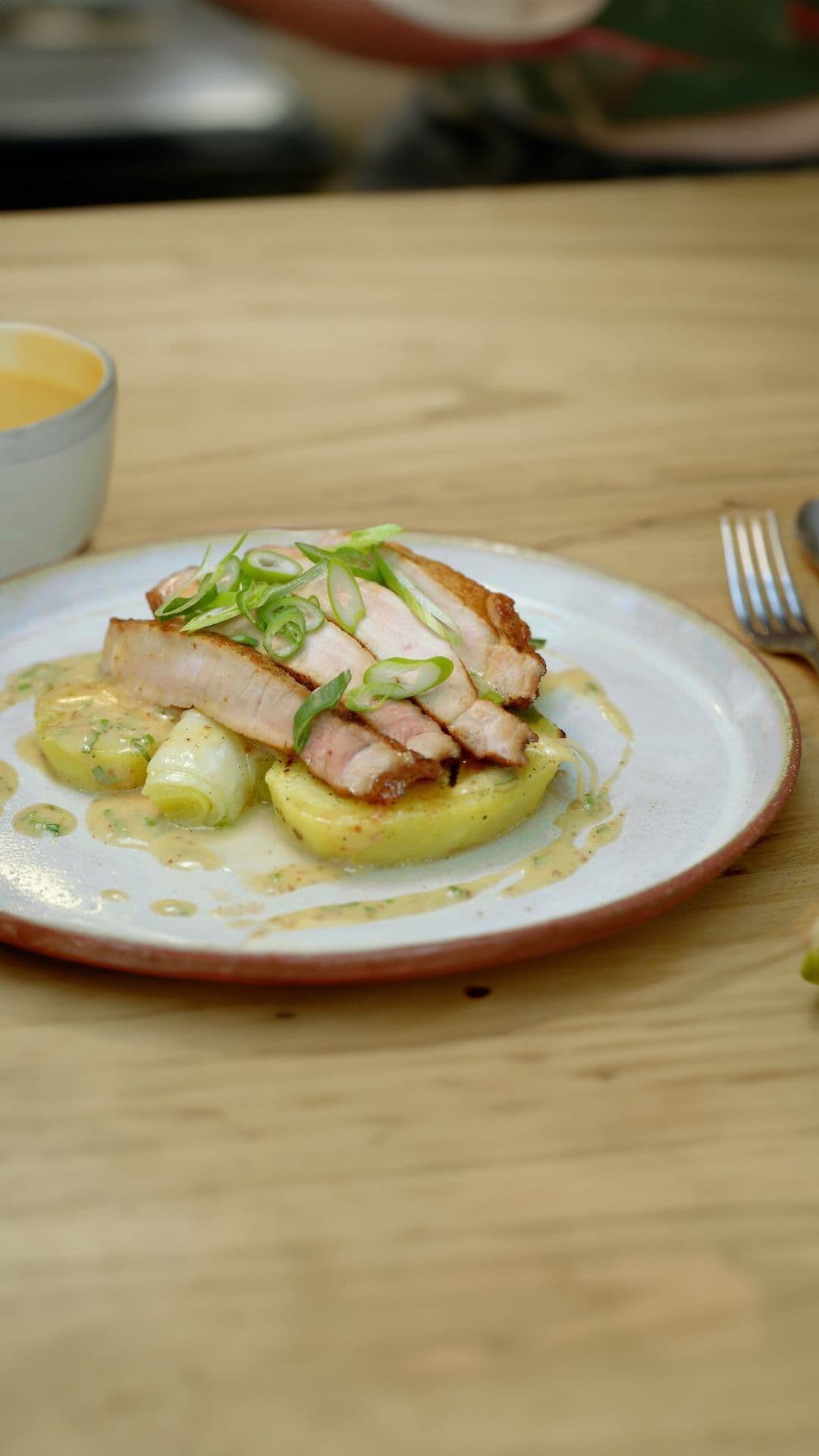 Varkenskotelet met prei, mosterdvinaigrette en aardappelschijfjes