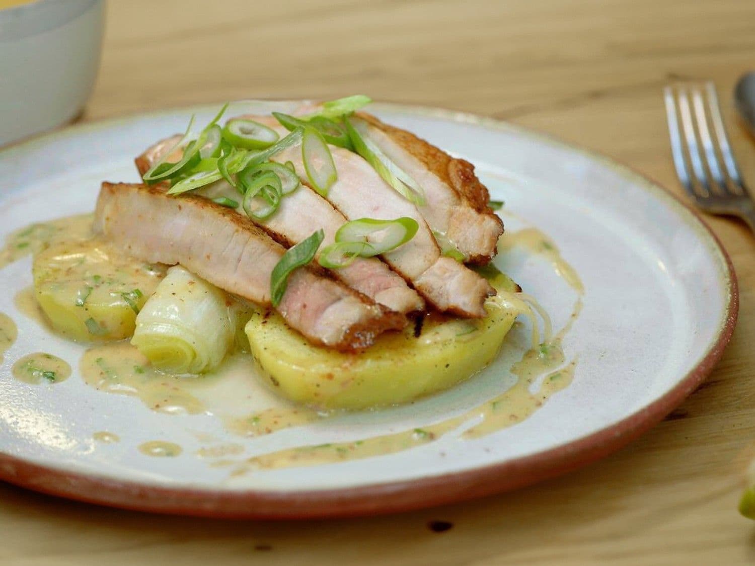 Varkenskotelet met prei, mosterdvinaigrette en aardappelschijfjes