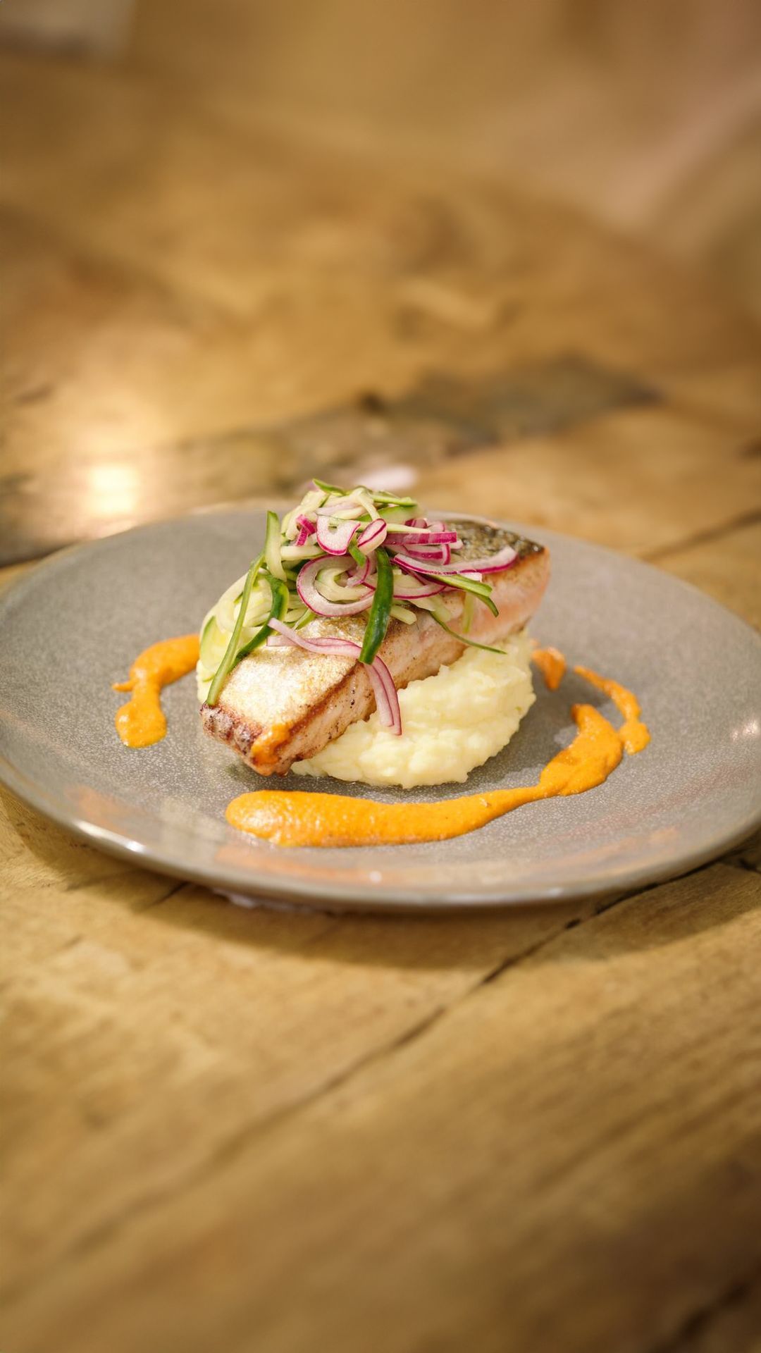 Zalm met komkommersalade, geitenkaaspuree en romescosaus