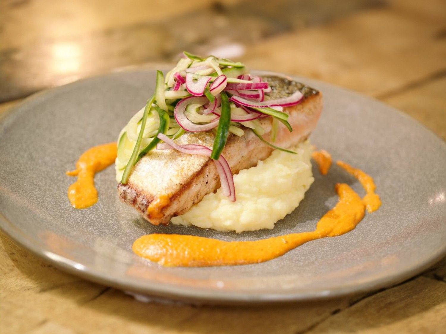 Zalm met komkommersalade, geitenkaaspuree en romescosaus