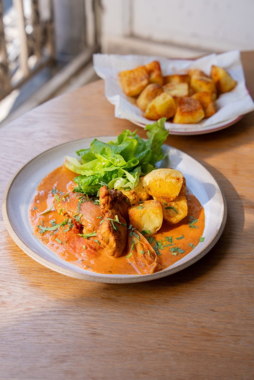 Kip in romige tomatensaus met gebakken aardappelen en sla