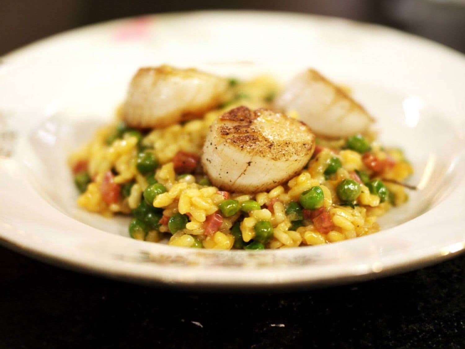 Sint-jakobsnootjes en risotto met erwtjes, chorizo en munt