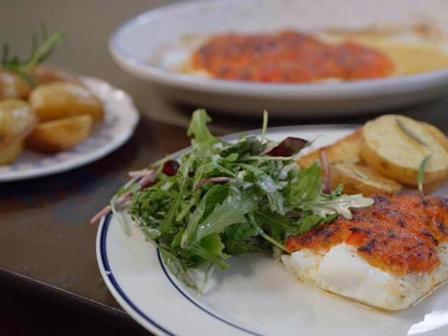 Schelvis met panade van gekonfijte paprika en parmezaan, mesclun en gebakken aardappel