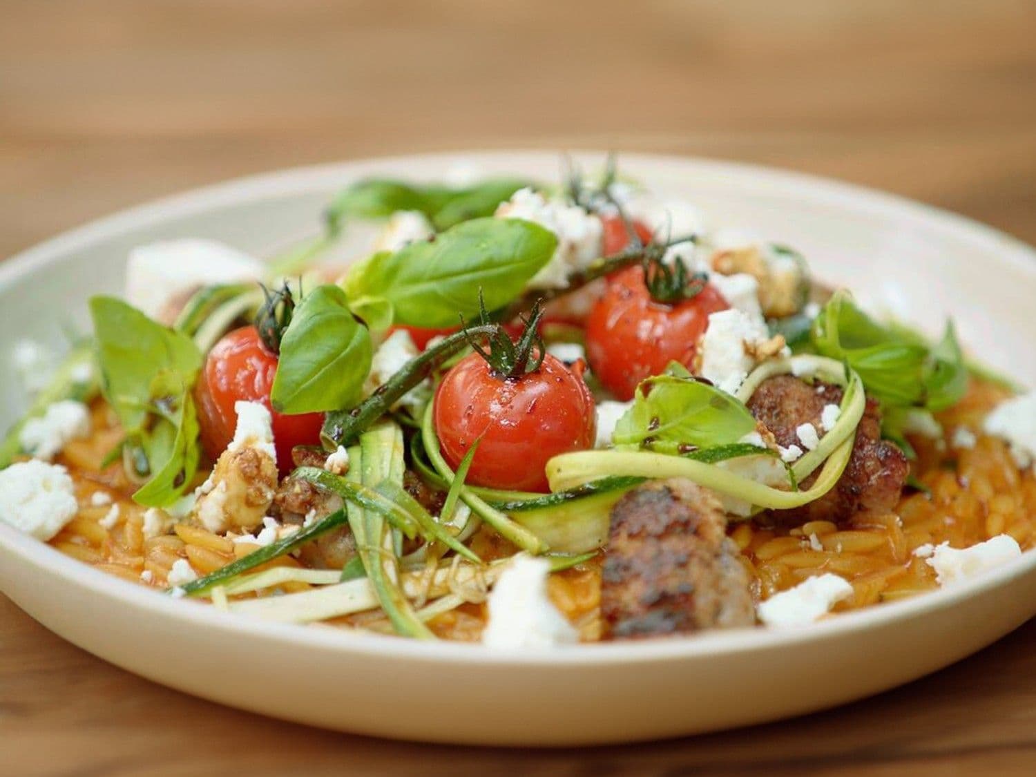 Orzo-risotto met salsiccia, kerstomaten, courgette en feta