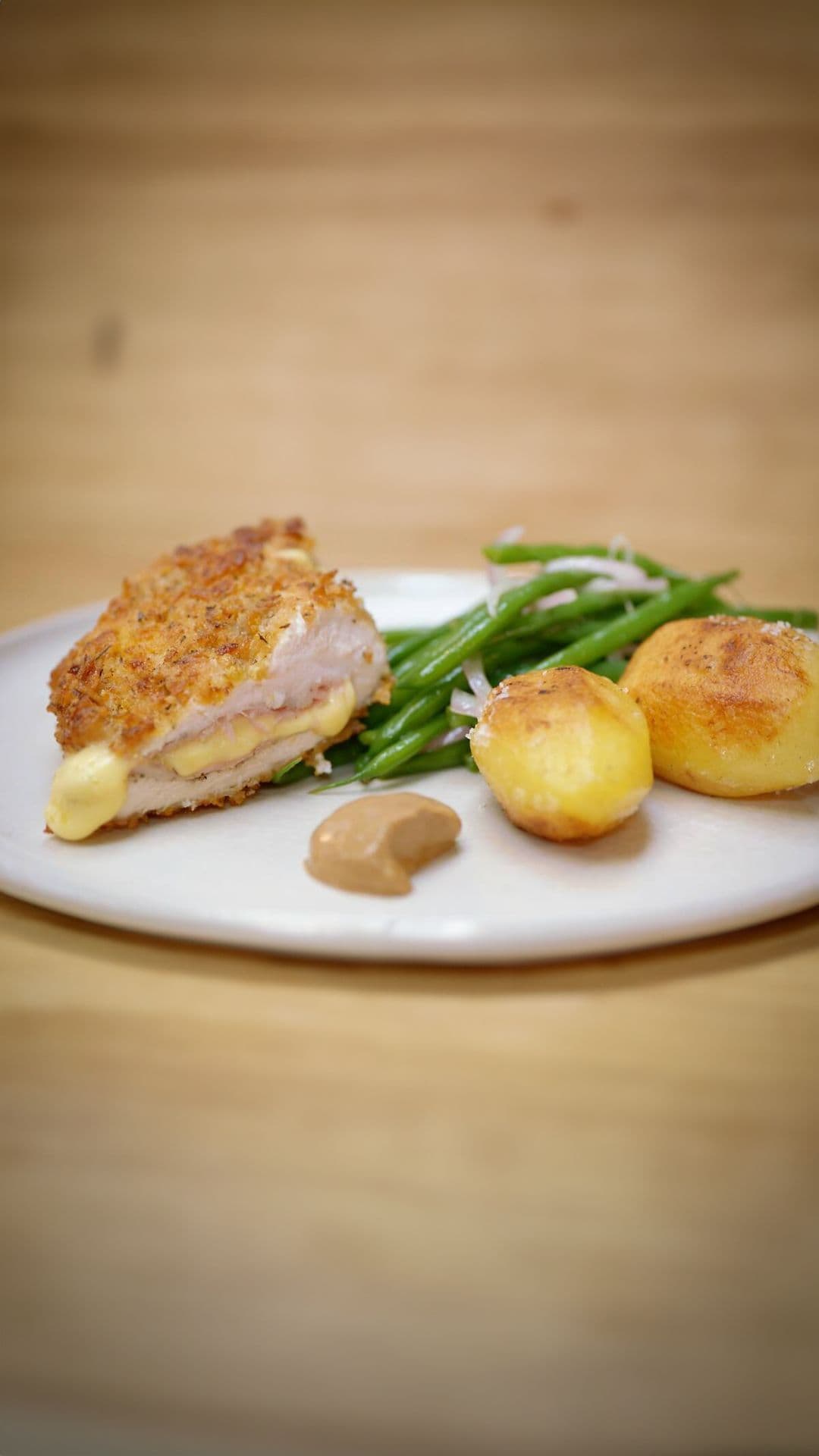 Gepaneerde kip met ham en kaas, gebakken aardappelen en boontjes