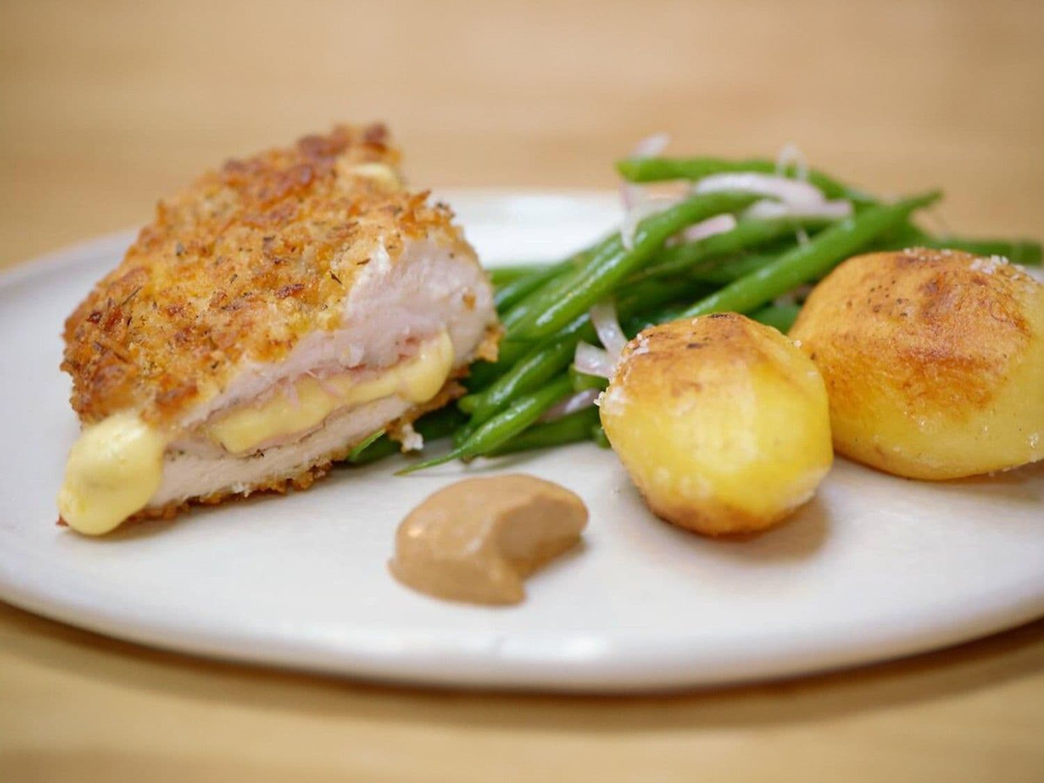 Gepaneerde kip met ham en kaas, gebakken aardappelen en boontjes