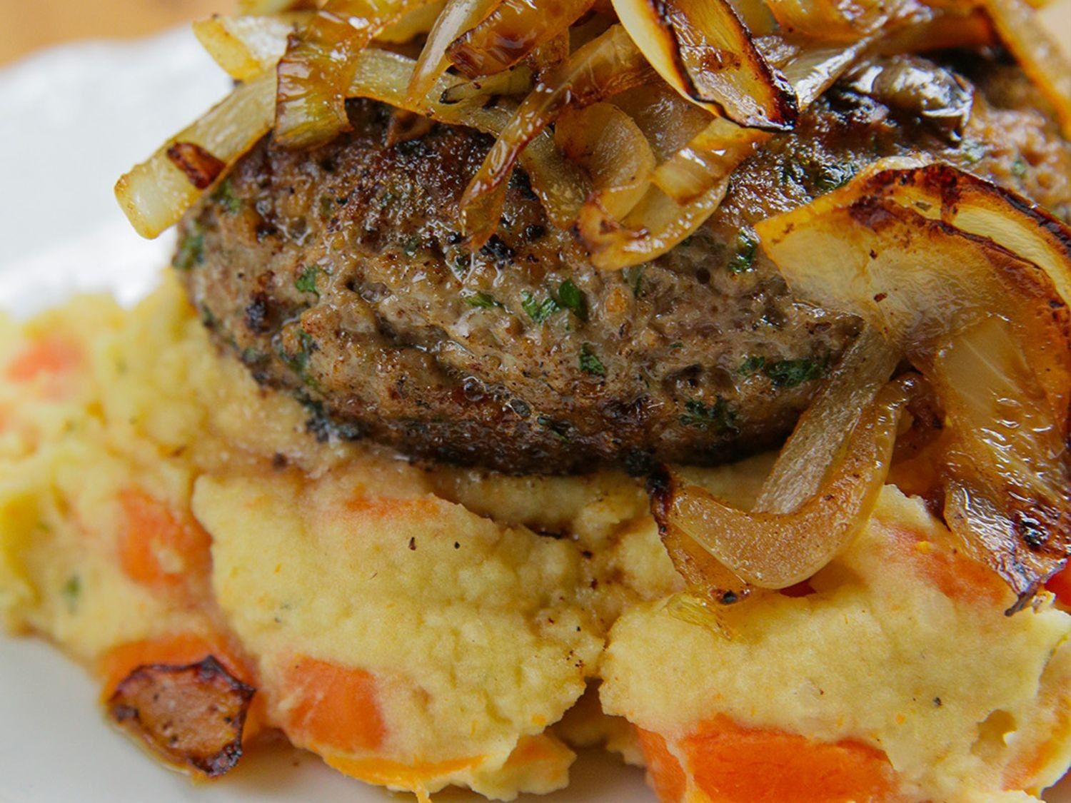 Hamburger met wortelpuree en gebakken ui