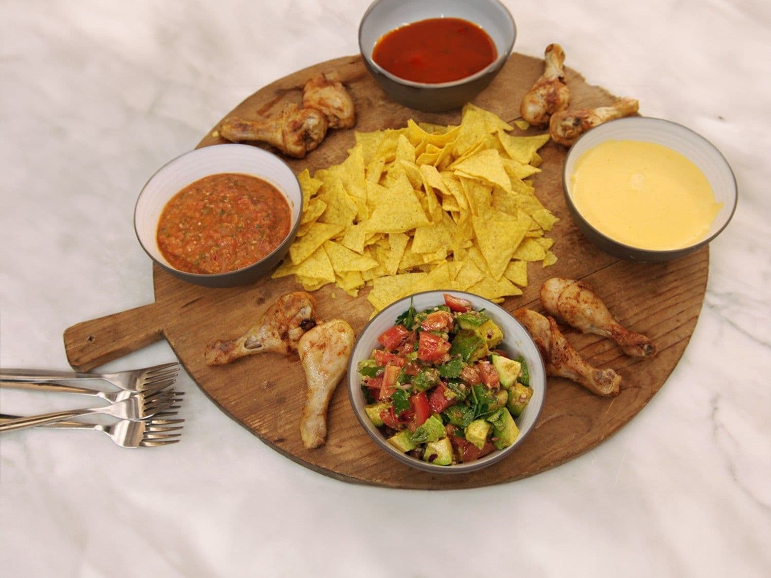 Nacho’s met kaasdip, tomatensalsa, drumsticks en sweet chili